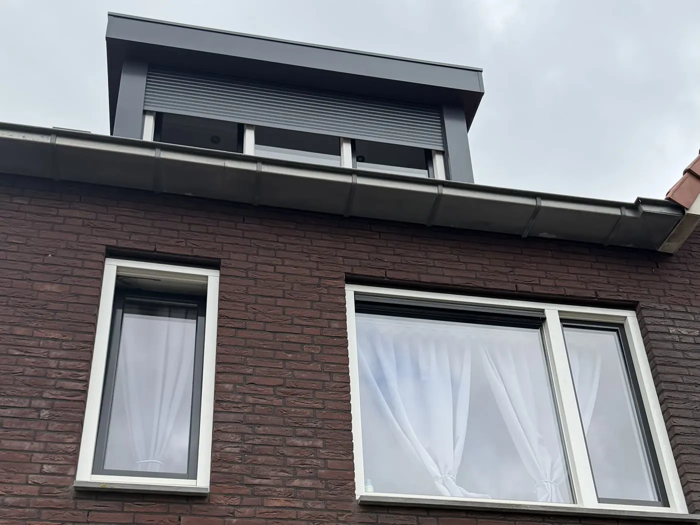 Voorgevel vóór de montage: twee ramen op de eerste verdieping zonder rolluiken; de dakkapel heeft al een rolluik